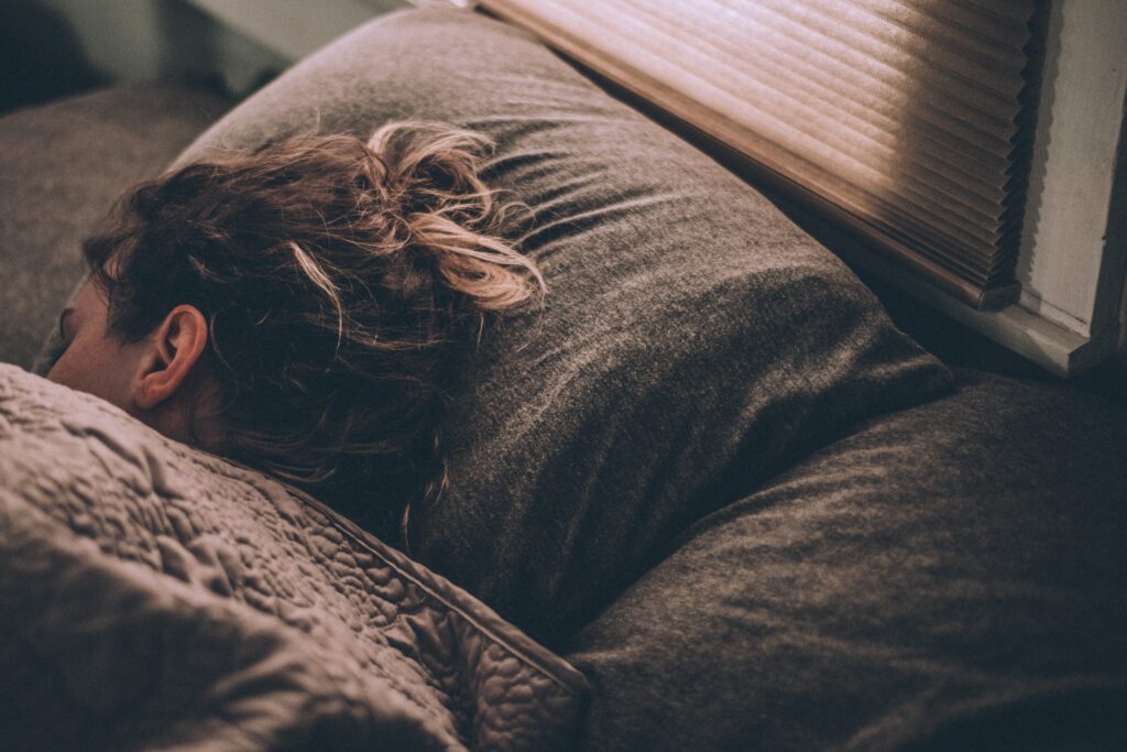 Woman sleeping in bed under the covers with head on pillow.