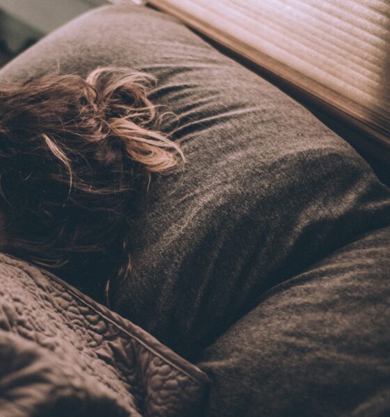 Woman sleeping in bed under the covers with head on pillow.