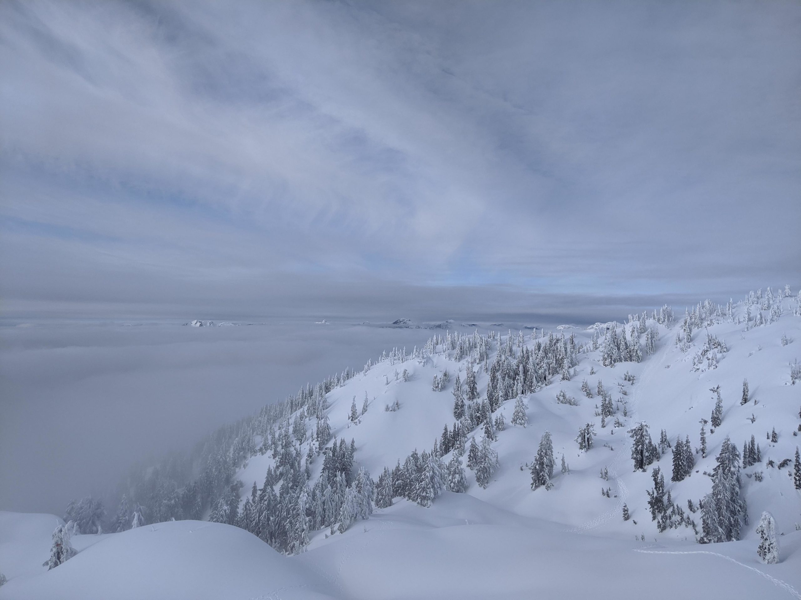A shot of a peak on Mount Seymour with clouds hanging around the mountain.